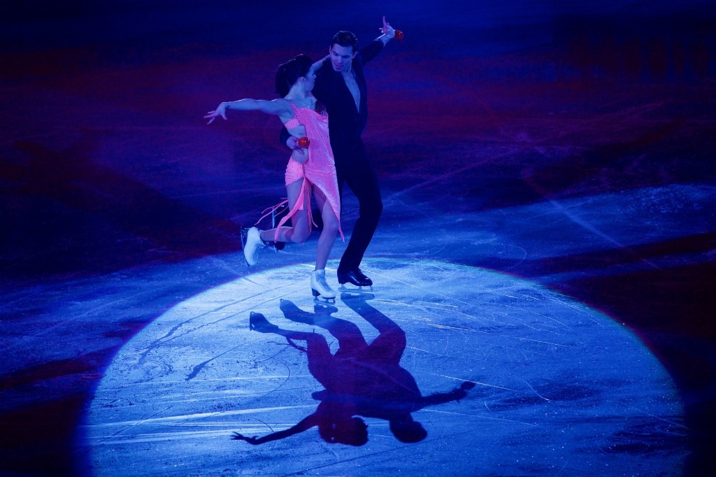 Figure skating pair performing under spotlight on ice