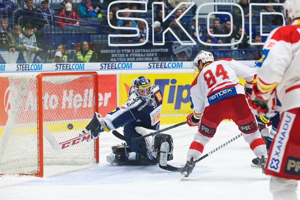 Ice hockey goalie stretching for a save as the puck approaches the net