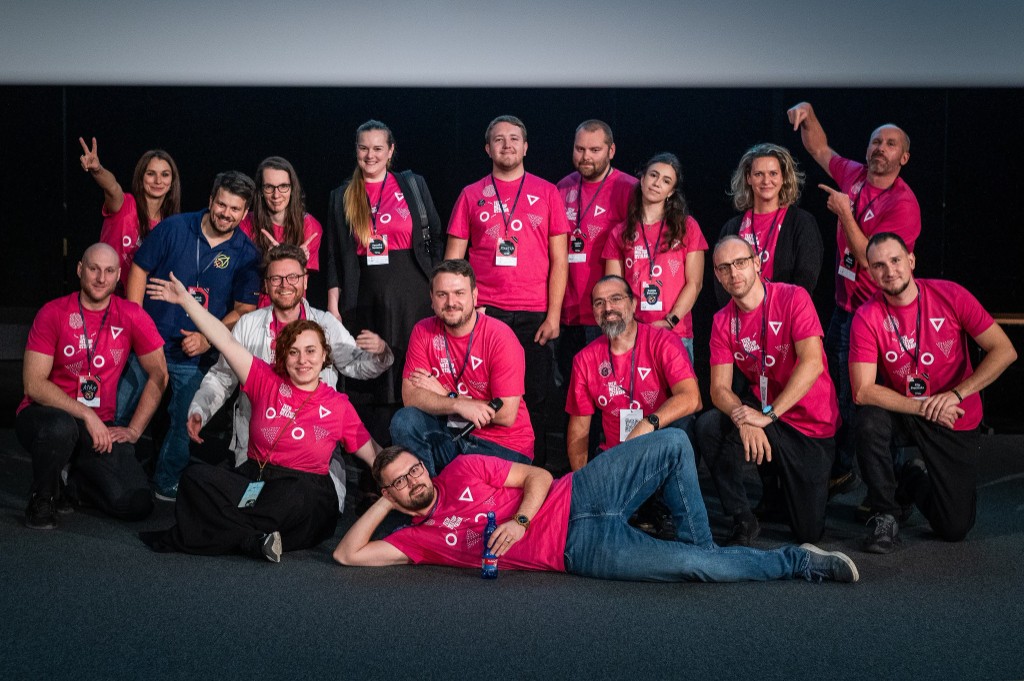 Organizing team in matching event shirts posing together in front of a stage