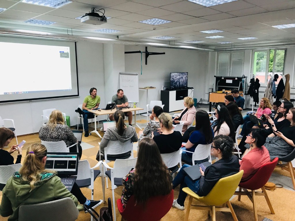 Technical classroom session with two instructors at the front and participants with laptops in a semicircle