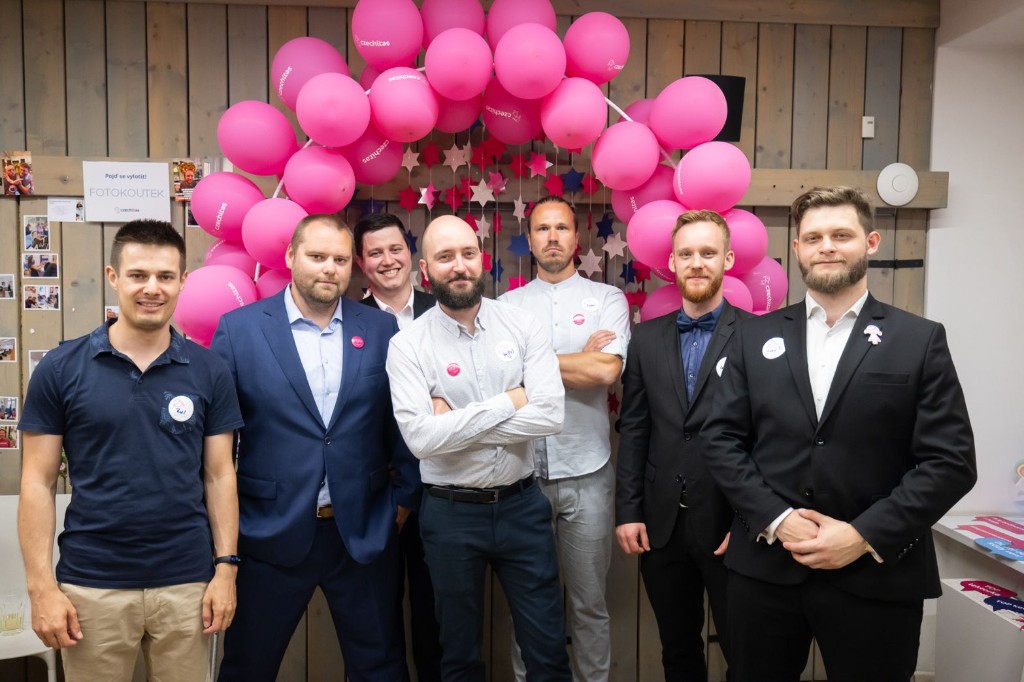 Group of instructors in front of a Czechitas balloon arch at an event photo booth