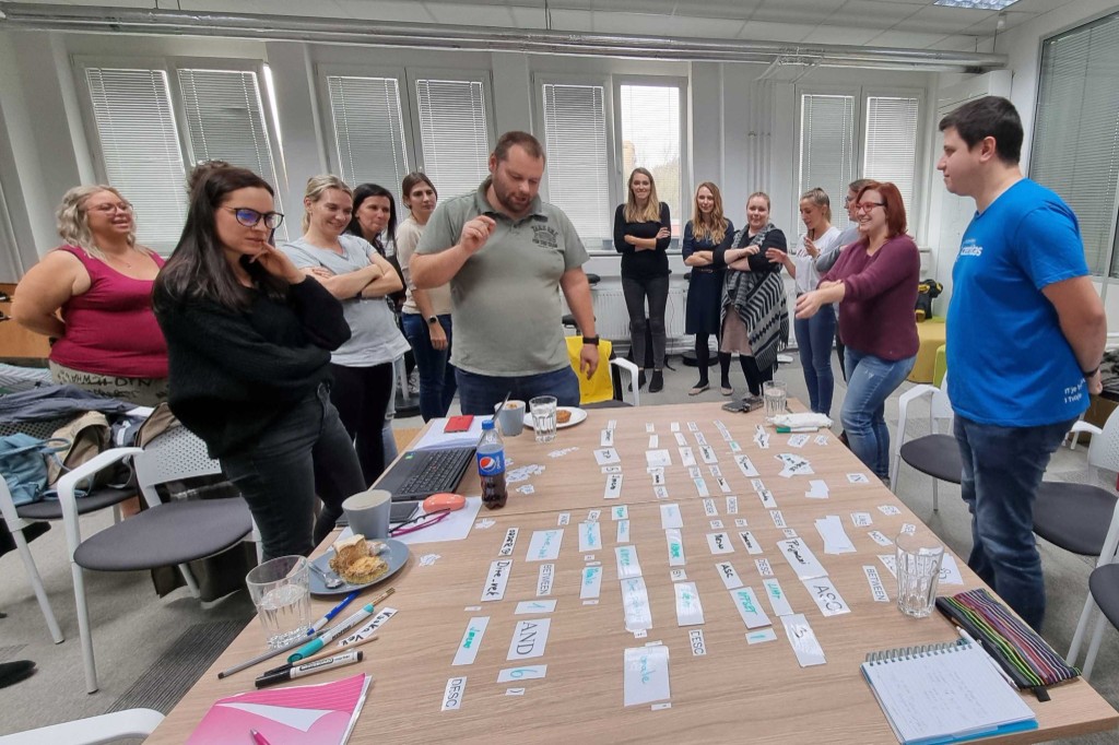Hands-on SQL workshop with Czechitas: participants and instructors around a table with SQL command cards
