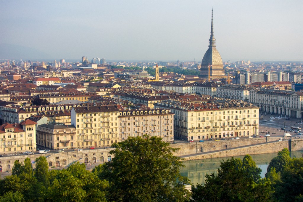Panoramic view of Turin, Italy, with the Mole Antonelliana spire above historic rooftops and the Po river
